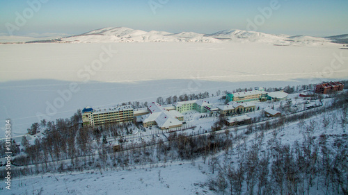 Resort on frozen lake in the mountains. Aerial. Ural, Russia