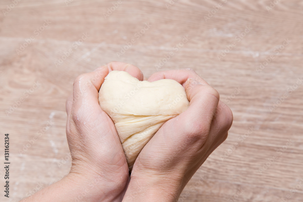 Hands holding the dough heart. Dough is ready for baking. Homemade pastries for Christmas time in the kitchen. Healthy eating lifestyle. Hands holding the dough heart. Dough is ready for baking. Homemade pastries for Christmas time in the kitchen. Healthy eating lifestyle.