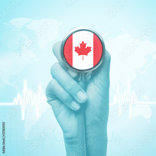 hand of doctor holding stethoscope with Canada flag.