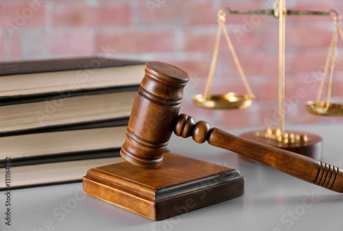 Gavel with books and scales on brick wall background