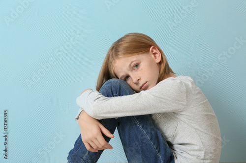 Upset girl sitting on blue ...