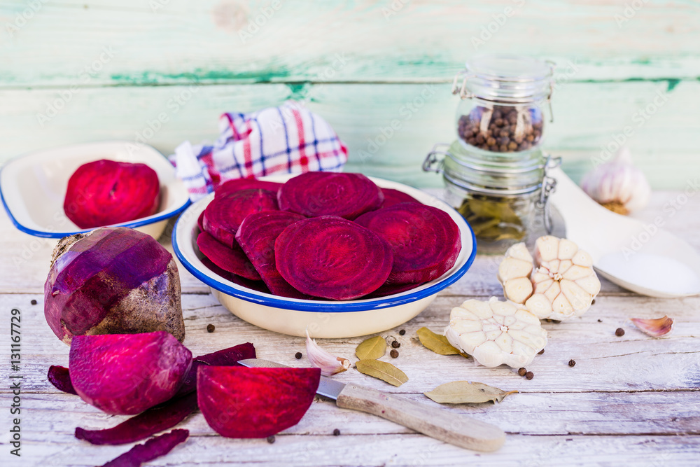 Sliced red beets and spices ready for cooking on rustic wooden background.