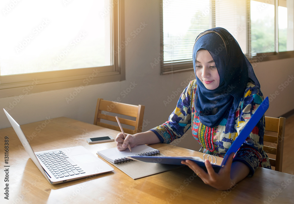 Muslim woman working with computer in the room, writing notebook. Muslim woman working with computer in the room, writing notebook.