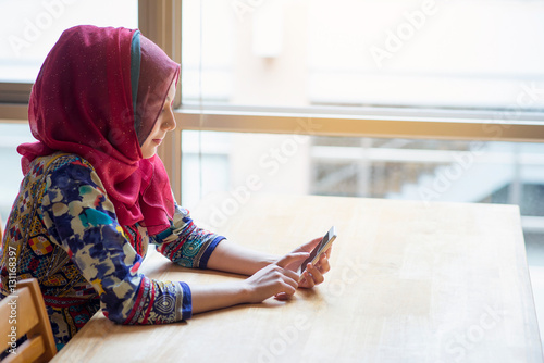 Muslim woman using and touching mobile phone.