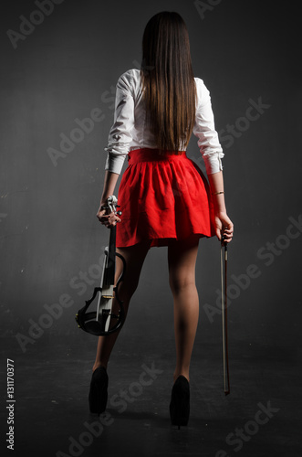 Girl stands back to the photographer with violin