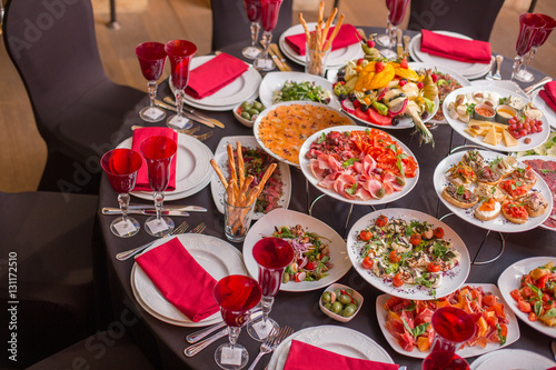 round table decorated with red wine glasses, a black tablecloth and italian dishes
