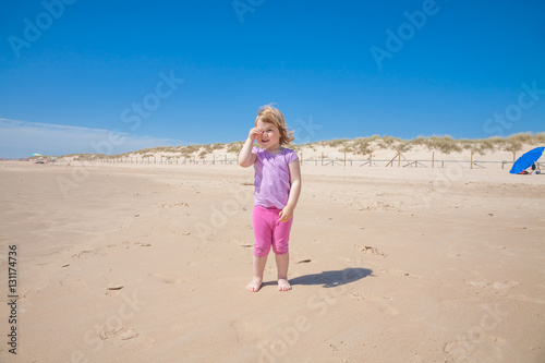 little girl playing with hand in eye at beach as spyglass