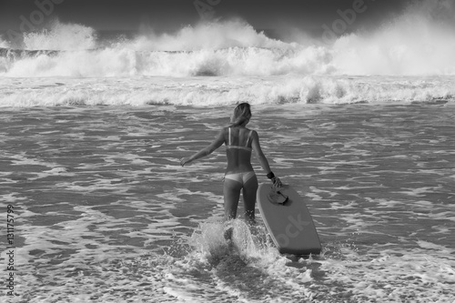 the girl walks into the ocean with a Board