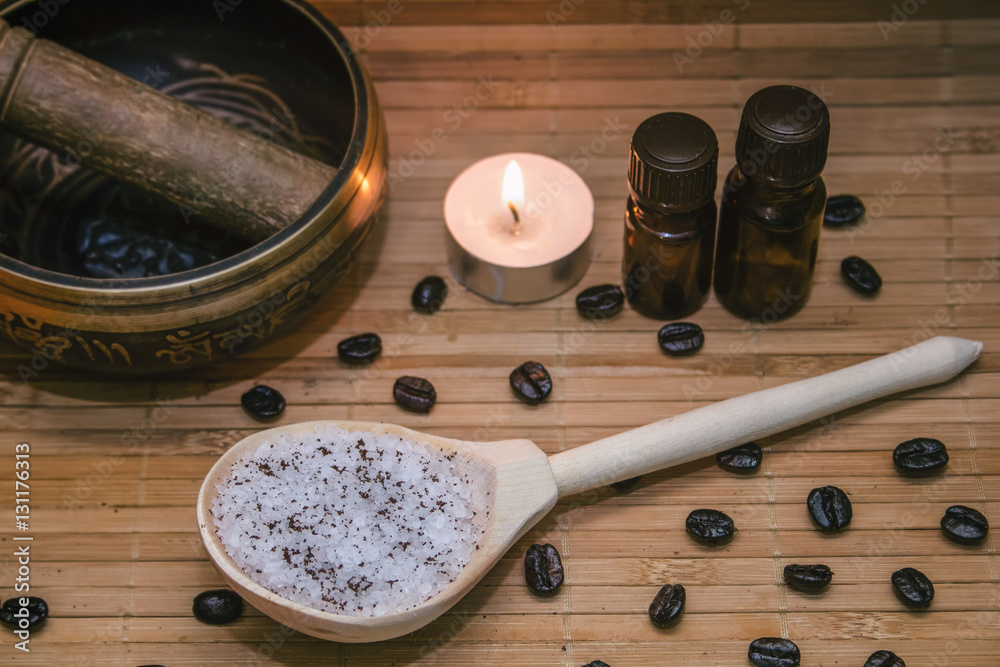Spa concept.Coffee scrub, coffee beans, singing bowl, aroma oil, candle on straw mat background Spa concept.Coffee scrub, coffee beans, singing bowl, aroma oil, candle on straw mat background