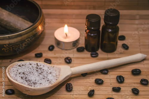 Spa concept.Coffee scrub, coffee beans, singing bowl, aroma oil, candle on straw mat background