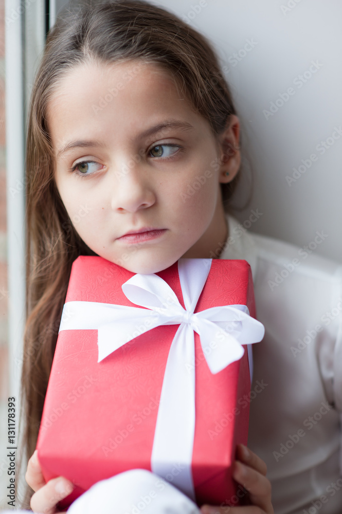 pretty little girl dreaming by the window holding gift pretty little girl dreaming by the window holding gift