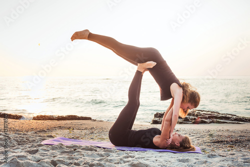 two young caucasian females practicing yoga on beach  © kurapatka
