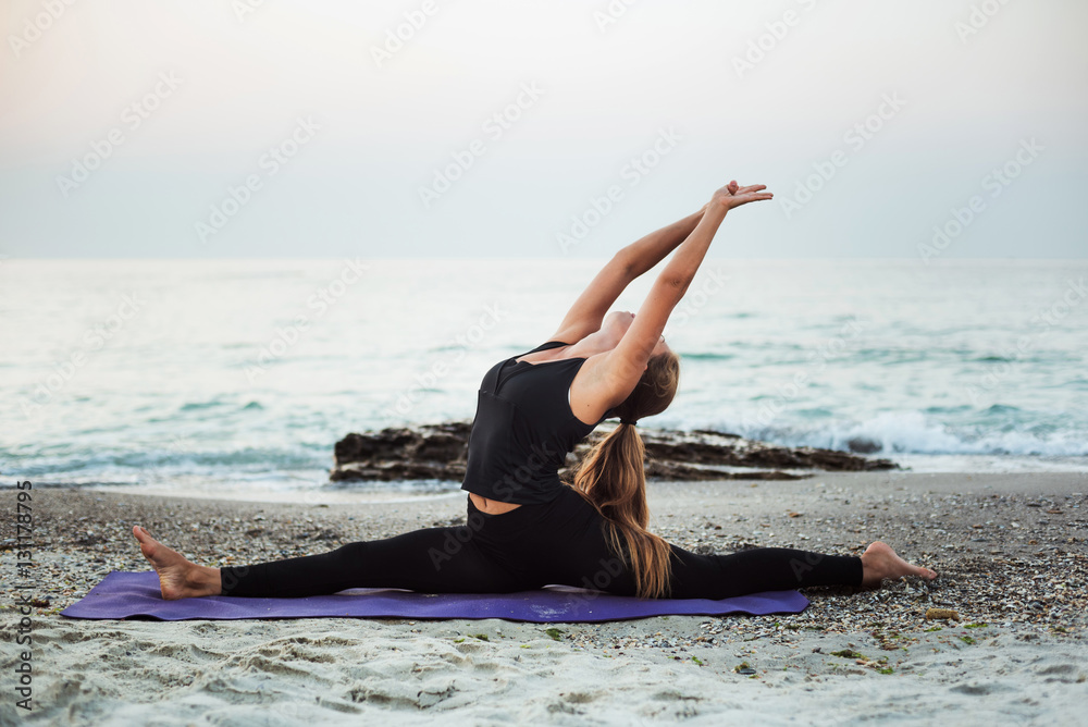 young caucasian female practicing yoga on the beach