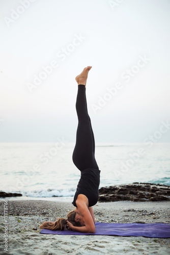 young caucasian female practicing yoga on the beach © kurapatka