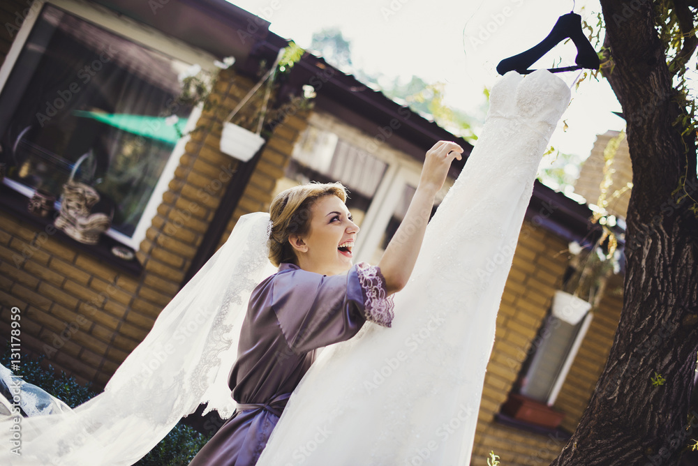 Bride in a bathrobe prepares to put on a wedding dress StockFoto