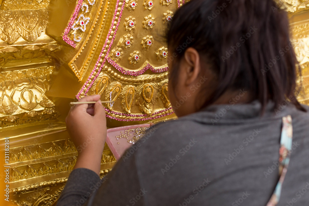 Woman handmade decorating the base of  Buddha statue