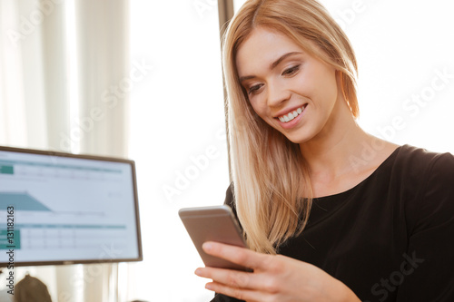 Cheerful young woman worker chatting by phone