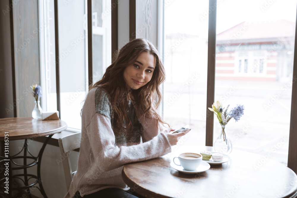 Beautiful young woman sitting at cafe while chatting by phone Beautiful young woman sitting at cafe while chatting by phone