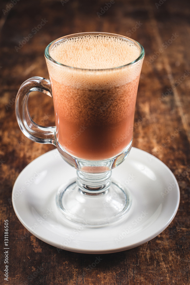 latte in a tall glass beaker on wooden table latte in a tall glass beaker on wooden table