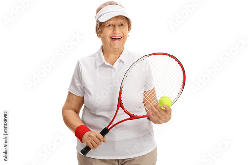 Joyful senior tennis player holding a racket and a tennis ball