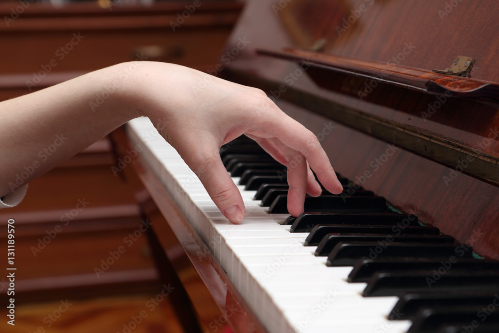Woman's hand on the keyboard of the piano closeup
