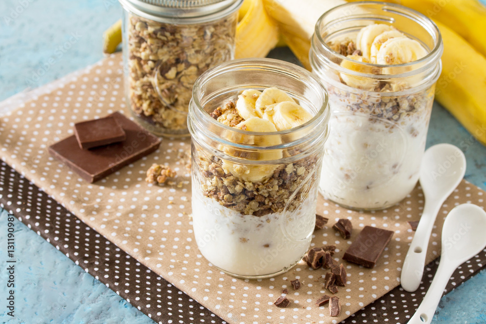 Granola. Granola with yogurt, chocolate and banana on blue concr Granola. Granola with yogurt, chocolate and banana on blue concr