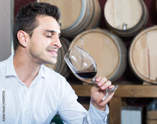 portrait of man tasting wine sample in glass in alcohol section