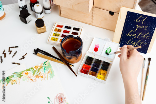 Girl painting flowers on paper with watercolor. photo