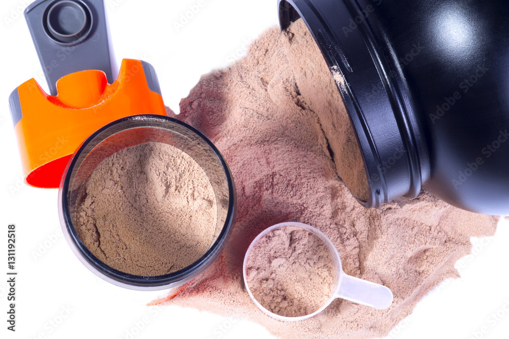 Sport nutrition image. Whey chocolate protein powder poured from protein  jar, opened orange sport shaker near with milk and protein, scoop with  powder near. Close up image. White background. Stock Photo