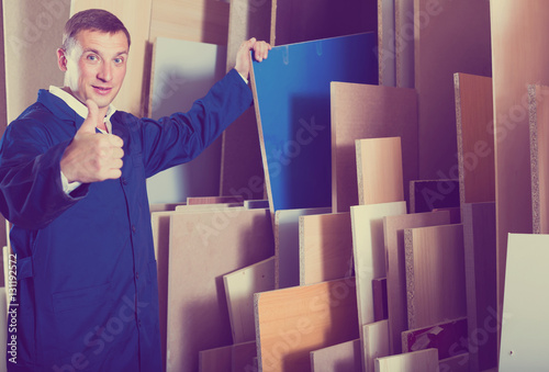 portrait of man in uniform choosing compressed densified wood in photo