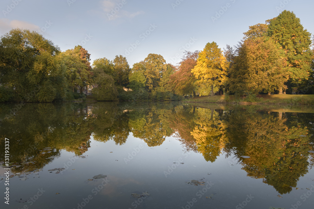 Autumn colored trees reflecting in park lake giving beautiful scenery
