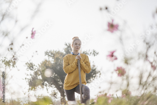 Young woman with spade in cottage garden