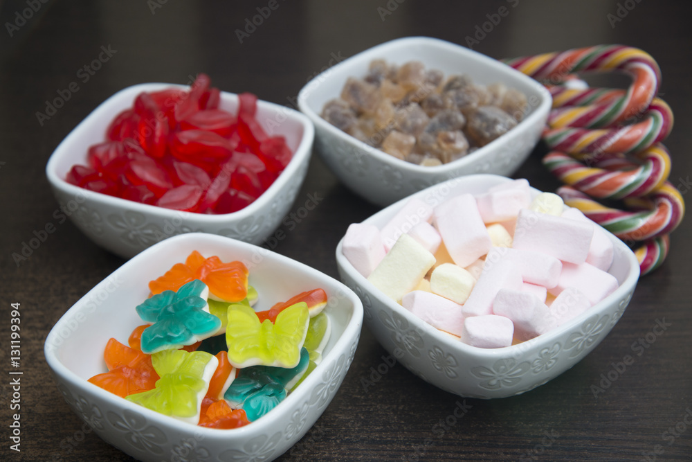 Many different sweets are in white bowls.