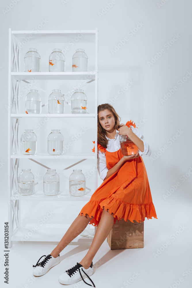 Relaxed woman sitting and holding glass jar with gold fish Relaxed woman sitting and holding glass jar with gold fish