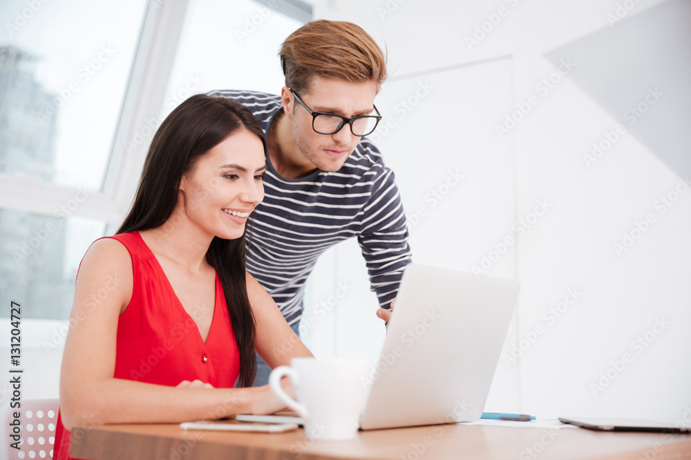 Couple by the table with laptop in office Couple by the table with laptop in office