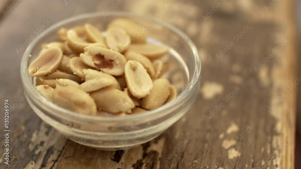 Close-up shot of salted fried peanuts in small bowl on wooden table Close-up shot of salted fried peanuts in small bowl on wooden table