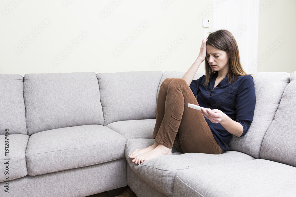 girl sitting on a couch at home while reading the results of her recent pregnancy test girl sitting on a couch at home while reading the results of her recent pregnancy test