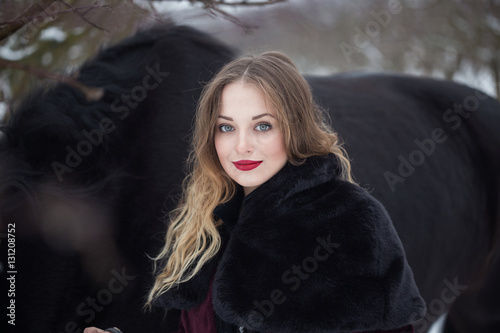 girl in dark clothes with a black horse
