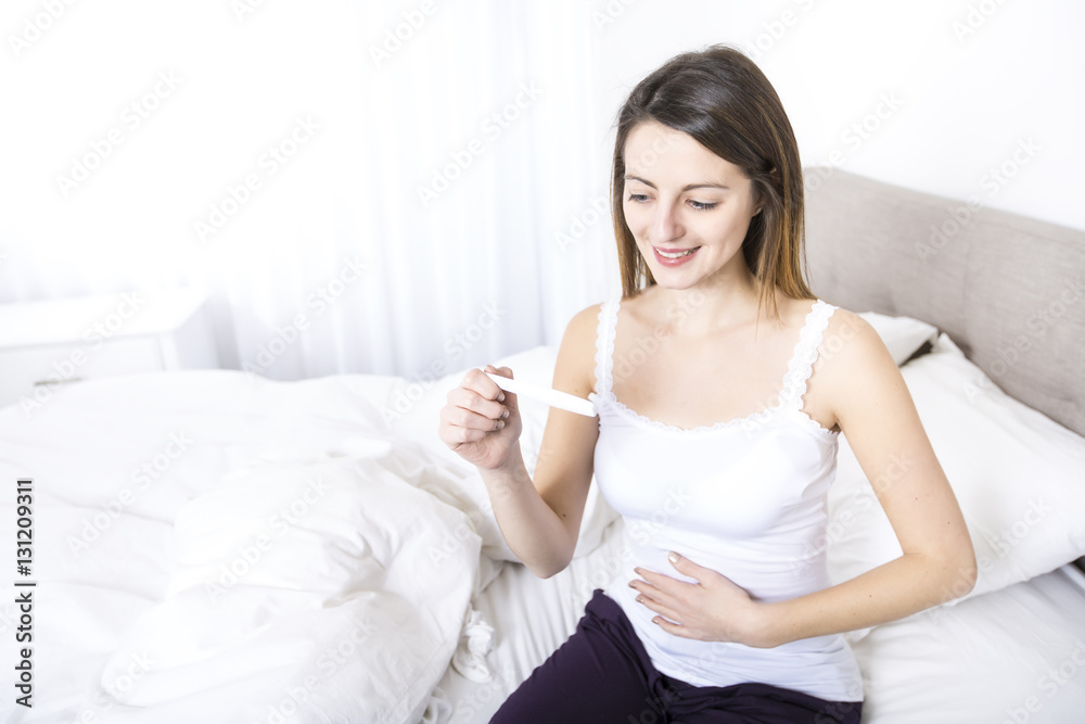 Young woman in bedroom at home wearing in white check pregnant test Young woman in bedroom at home wearing in white check pregnant test