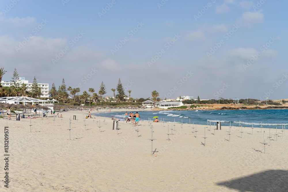 People sunbathe on Nissi Beach sand at sunny day. Ayia Napa, Cyprus.