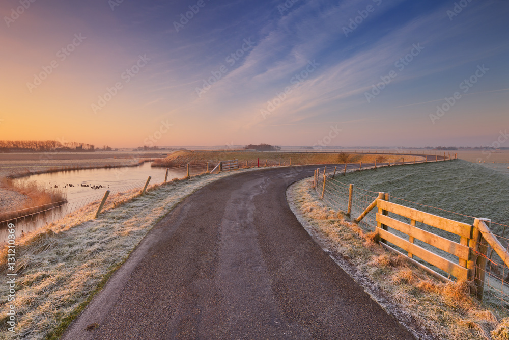 Typical Dutch landscape with a dike, in winter at sunrise