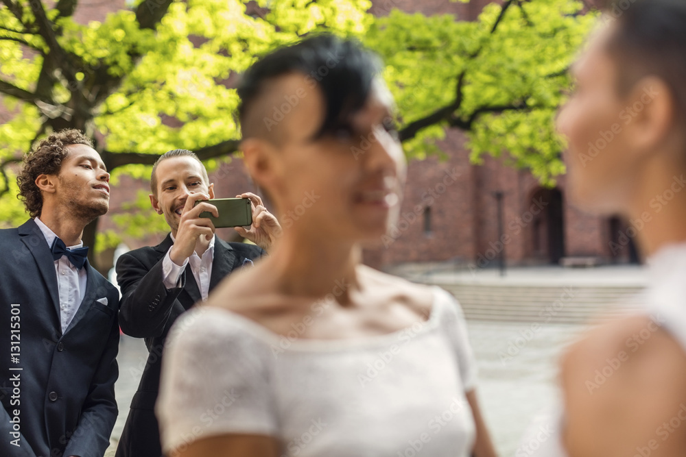 Male friend photographing lesbian couple during wedding ceremony