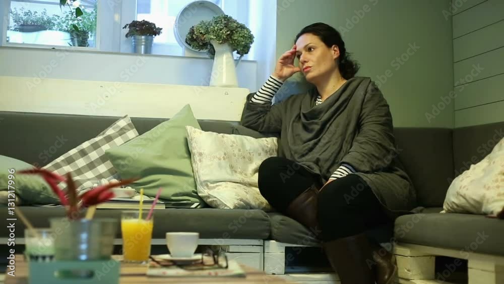 Sad, depressed woman sitting on sofa at cafe
