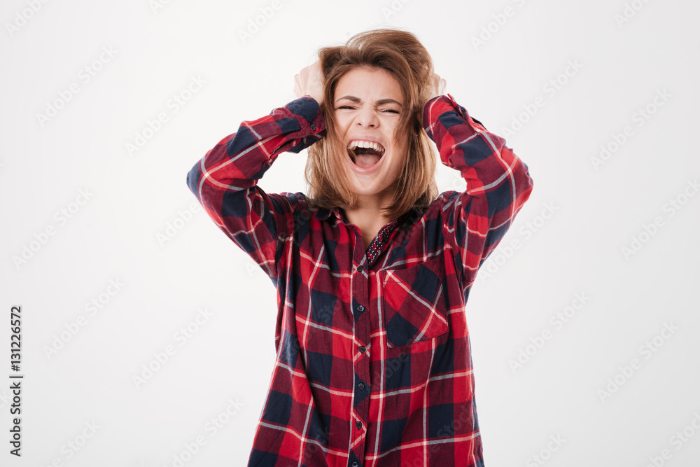 Stressed young woman with hands on head standing and shouting Stressed young woman with hands on head standing and shouting