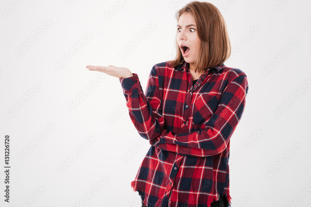 Surprised young woman holding copyspace on palm and looking away Surprised young woman holding copyspace on palm and looking away