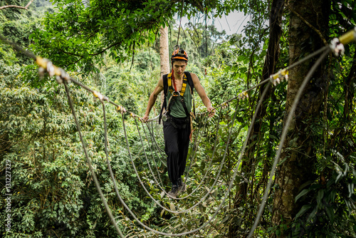 Man crossing rope bridge in forest, Ban Nongluang, Champassak province, Paksong, Laos photo