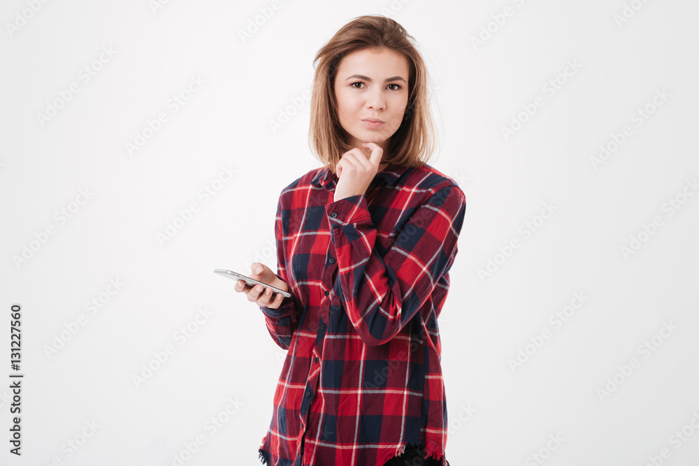 Girl in plaid shirt holding smartphone and looking at camera Girl in plaid shirt holding smartphone and looking at camera