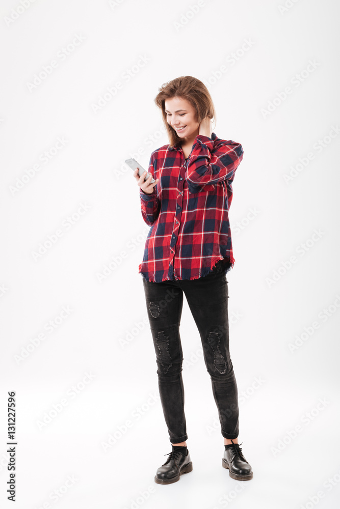 Woman in plaid shirt standing and using mobile phone Woman in plaid shirt standing and using mobile phone