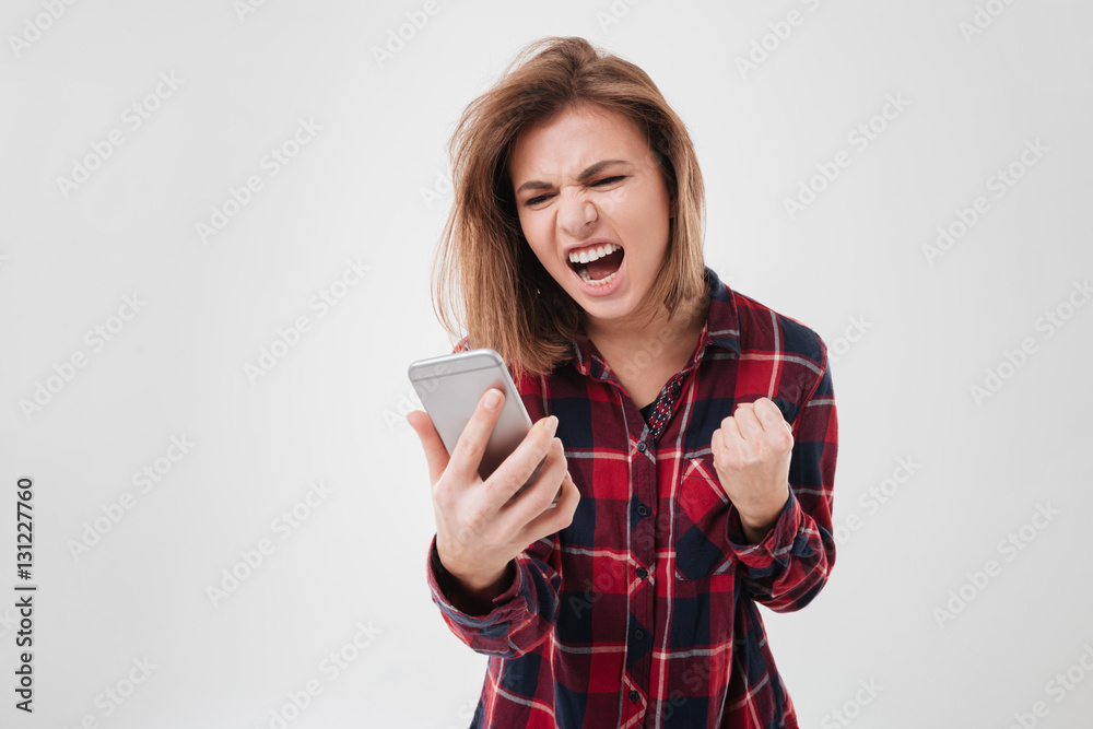 Young woman in plaid shirt shouting at mobile phone Young woman in plaid shirt shouting at mobile phone