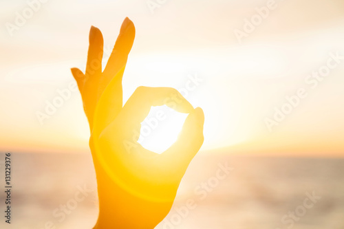 Woman circling the sun with fingers at sunrise